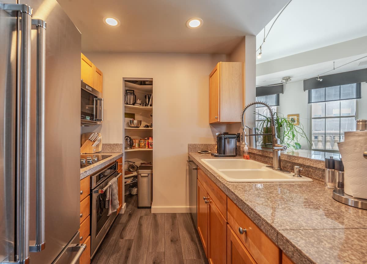 Full galley kitchen in the furnished residence with stainless-steel appliances, granite counters, and a Nespresso machine — equipped for long stays.