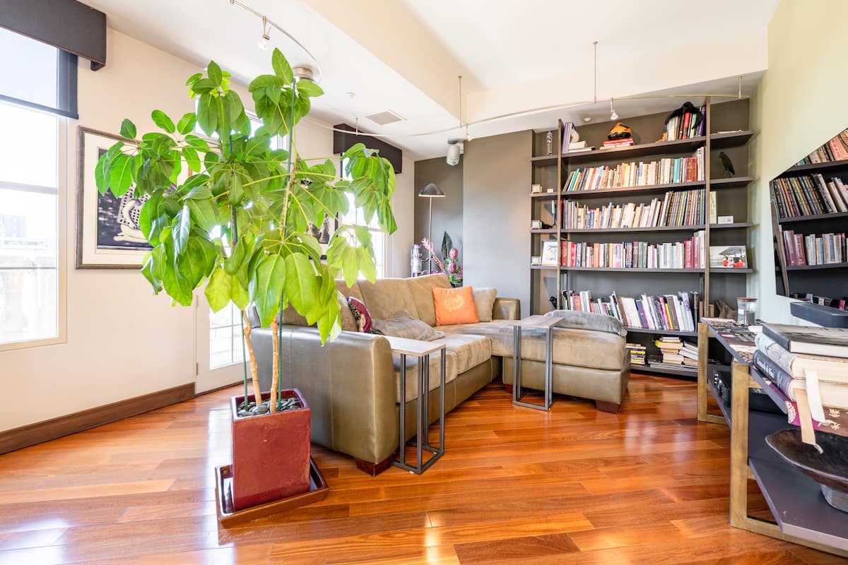 Living room reading corner with floor-to-ceiling built-in bookshelves, cherry hardwood, and a sectional sofa in the Golden Triangle residence.